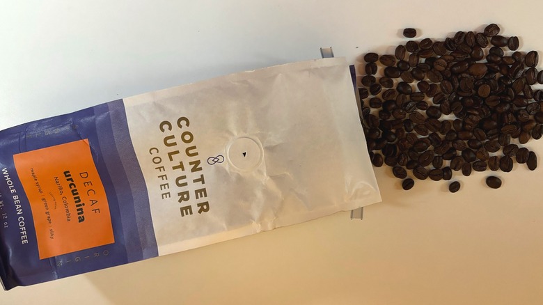 Coffee beans spilling out of a bag of Counter Culture coffee onto a white table