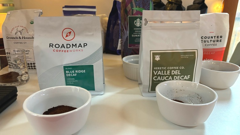 Coffee bags and cups of coffee grounds on a white table, preparing for coffee cupping