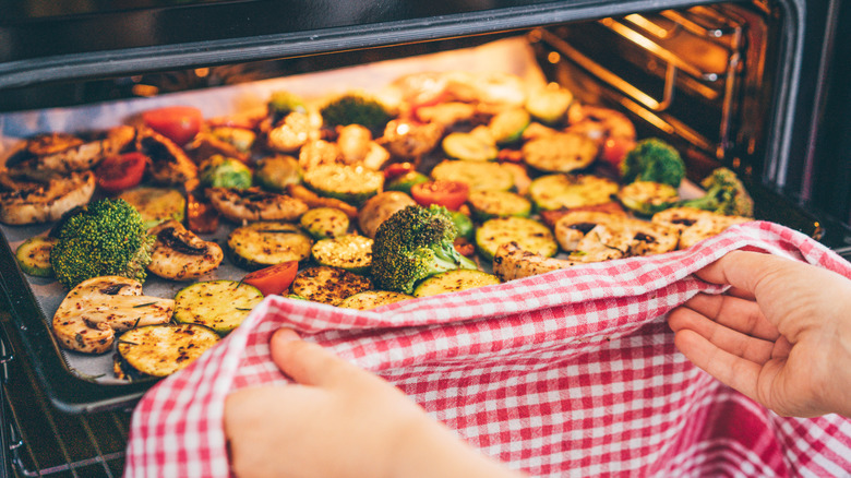 Removing sheet pan of roasted vegetables from oven