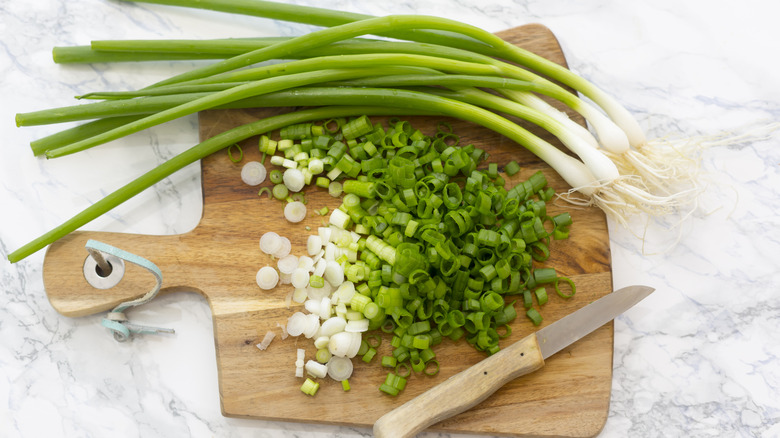 Freshly chopped green onions on wooden cutting board