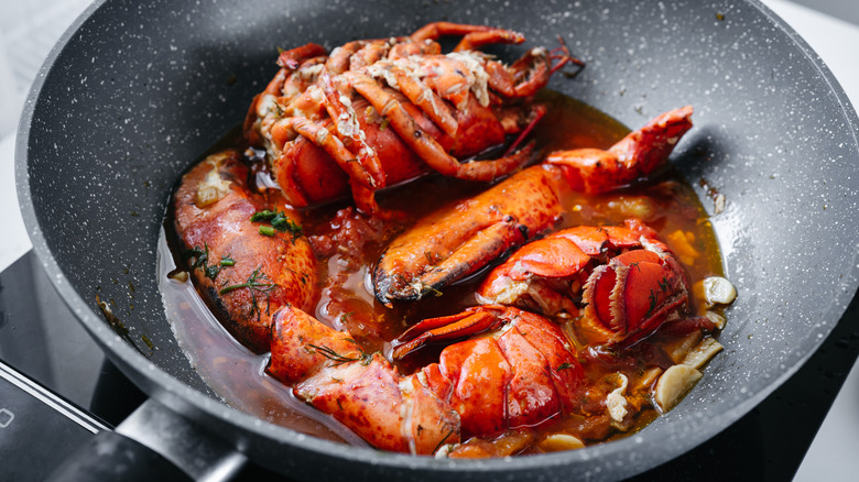 Lobster bodies and claws broken down in a frying pan