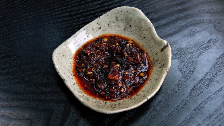 A dish with chili sauce on a dark wood table