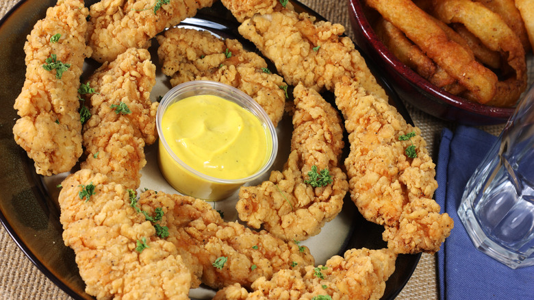 A plate with chicken tenders and honey mustard