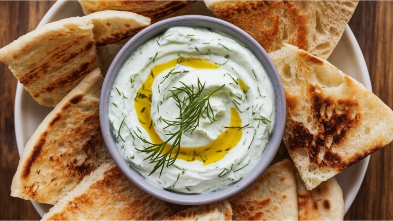 A plate with pita and tzatziki sauce with olive oil