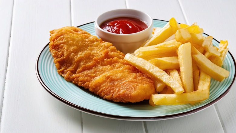 A plate of fish and chips with a side of ketchup