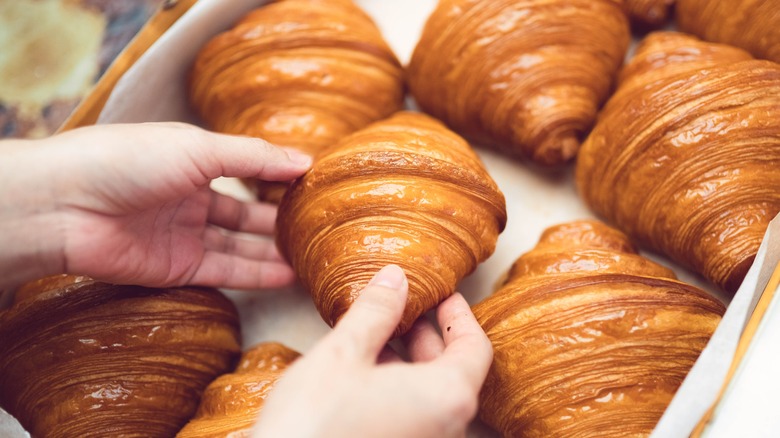 Person picking up a fresh croissant 