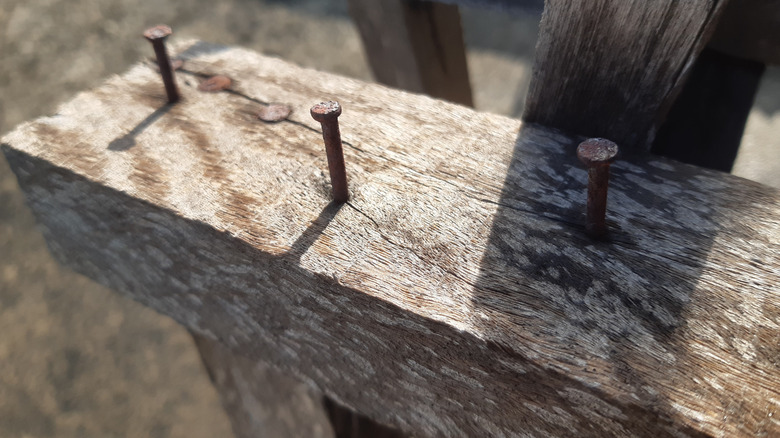 Plank of wood with nails protruding out of it