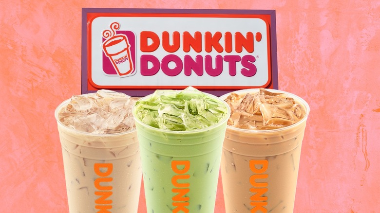 Three iced Dunkin' drinks underneath the chain's logo against an orange background