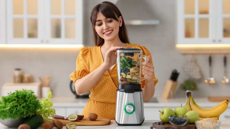 A woman mixing ingredients in a blender