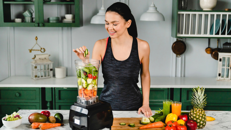 A woman adding ingredients to a blender
