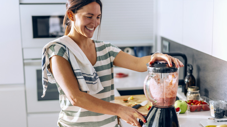 A woman starting a blender