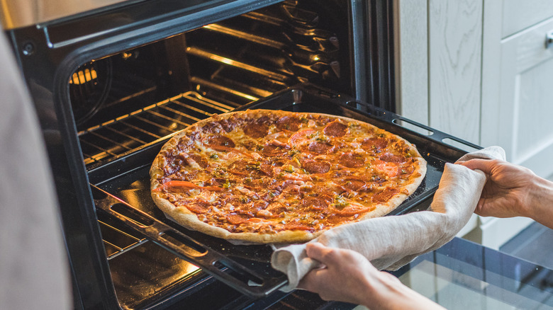 taking pizza out of the oven