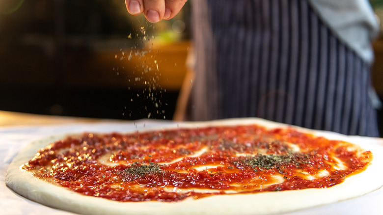 sprinkling dried oregano on pizza