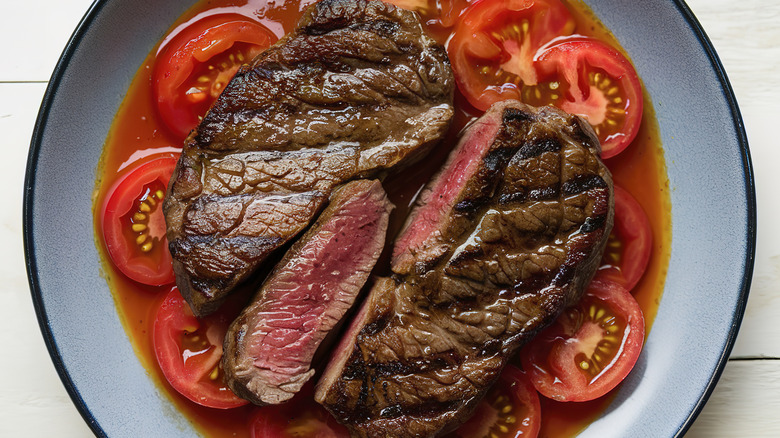 A cut steak on a bed of tomatoes
