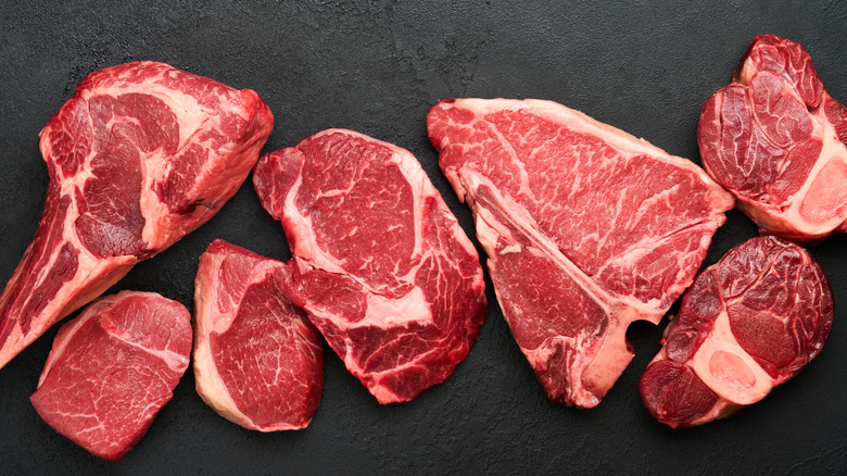 Various cuts of raw steak on slate