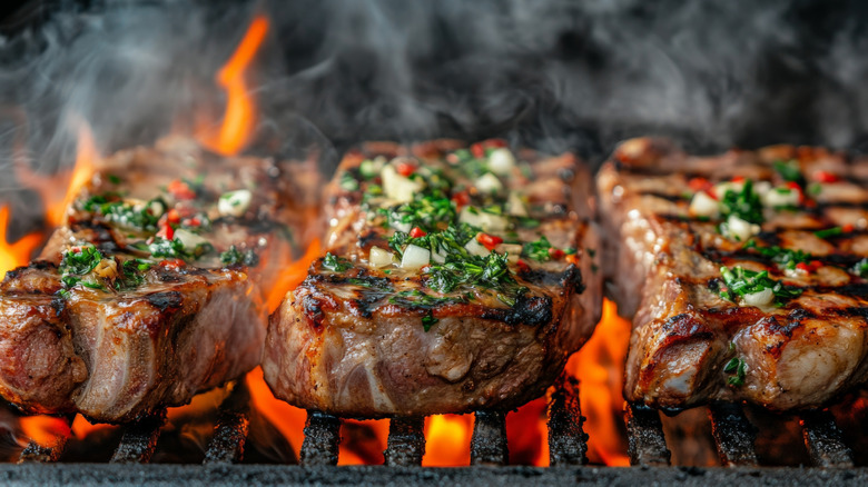 heavily seasoned steaks cooking on a coal grill
