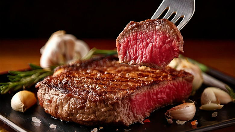 a steak on a plate with a piece of meat on a fork