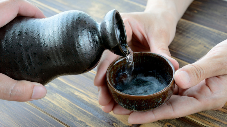 a person pouring sake into a bowl