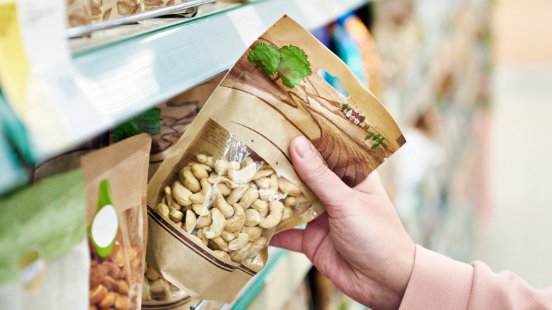 Hand grabbing cashews from shelf