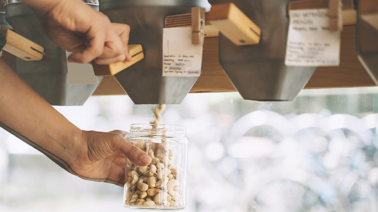 Hands dispensing cashews into jar