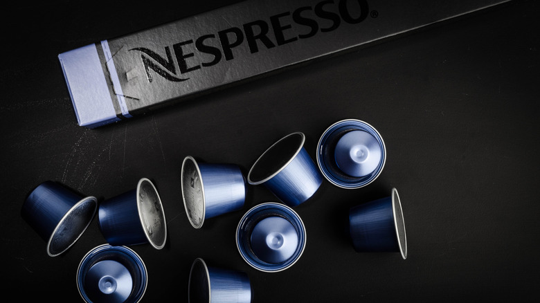 Dark blue Nespresso Lungo capsules next to black Nespresso sleeve on black table