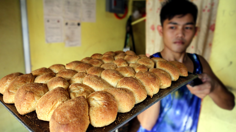 Worker holds a tray of pandesal