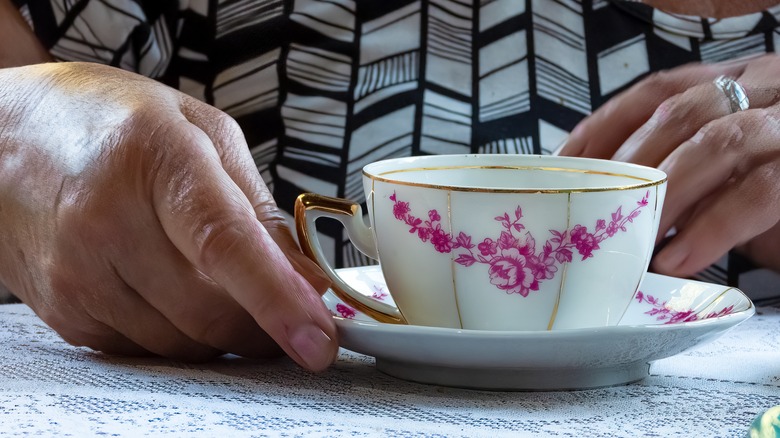 Person holding teacup and saucer