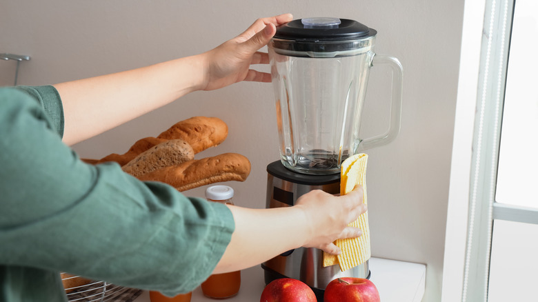 Person wiping down jug blender