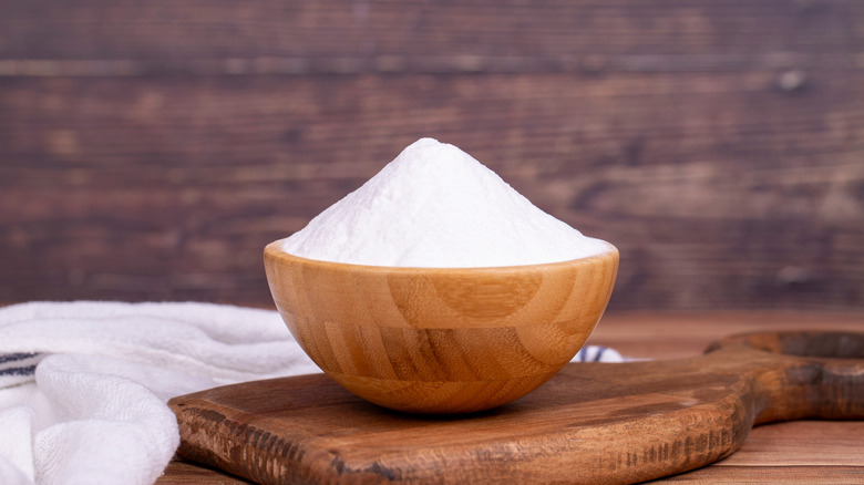 Baking soda in wooden bowl on top of wooden board