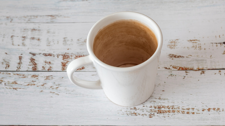 White mug showing the inside coated with tea stains