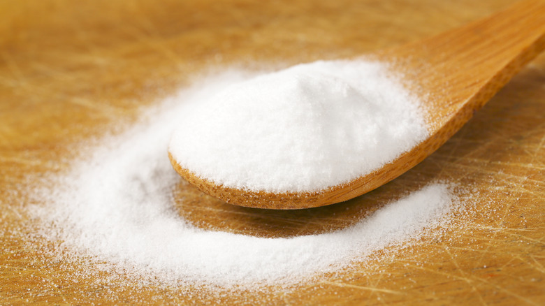 Wooden spoon filled with baking soda on cutting board