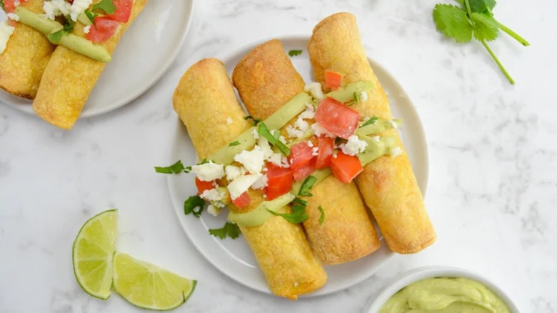 A plate with chicken taquitos and avocado creme