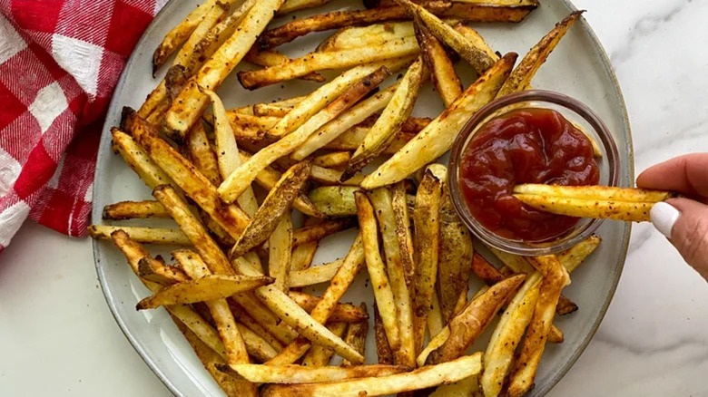 A plate with french fries and ketchup
