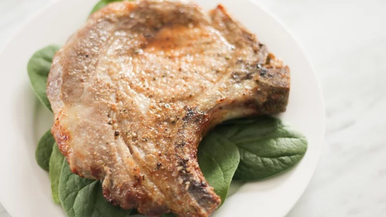 A pork chop on a bed of spinach