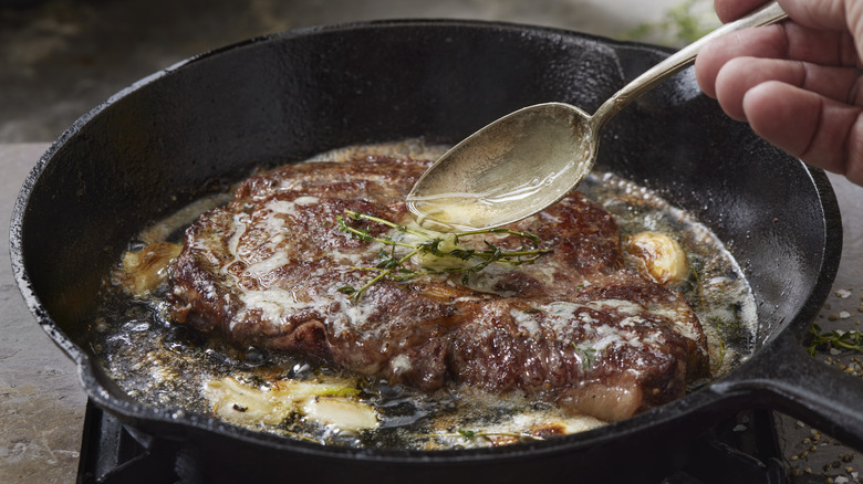 basting steak with butter in cast iron skillet