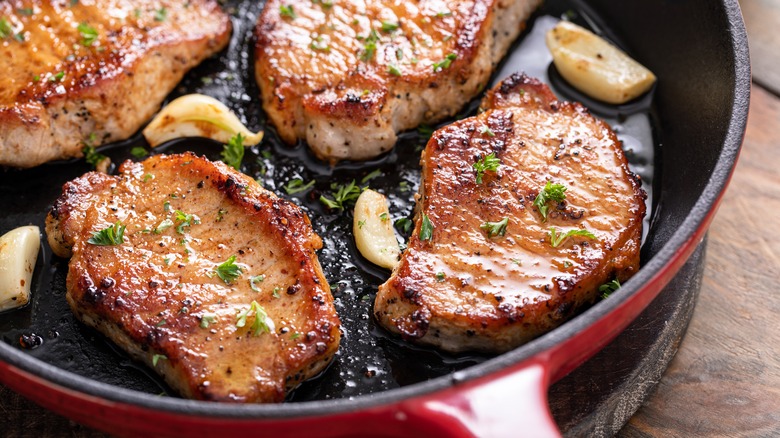 moist pork chops cooking in a skillet with garlic