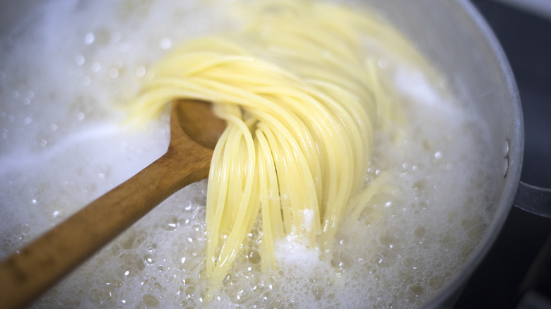 spaghetti on wooden spoon in boiling water