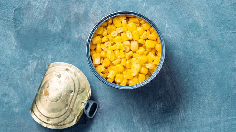 Canned corn with lid on blue background