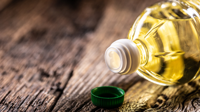 Overturned oil bottle with green cap on wooden surface