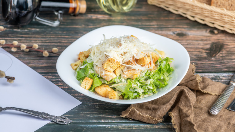 Tarditional Caesar salad on a white plate with vintage background