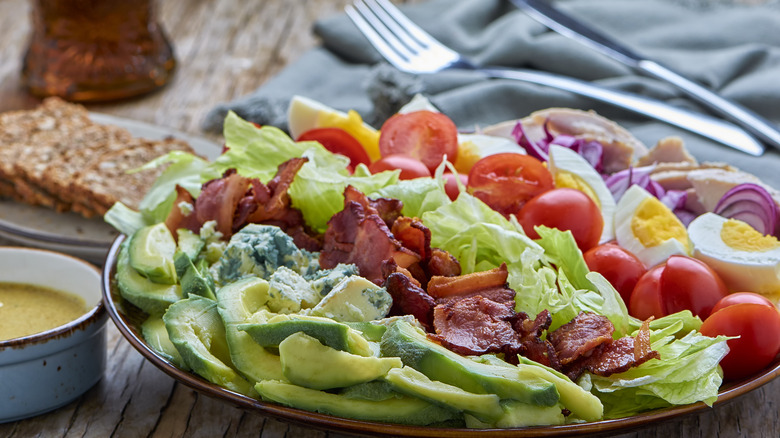 Traditional Cobb salad with dressing and utensils