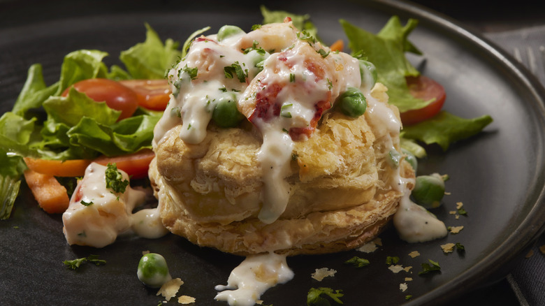 Lobster Newburg in a puff pastry next to light green salad