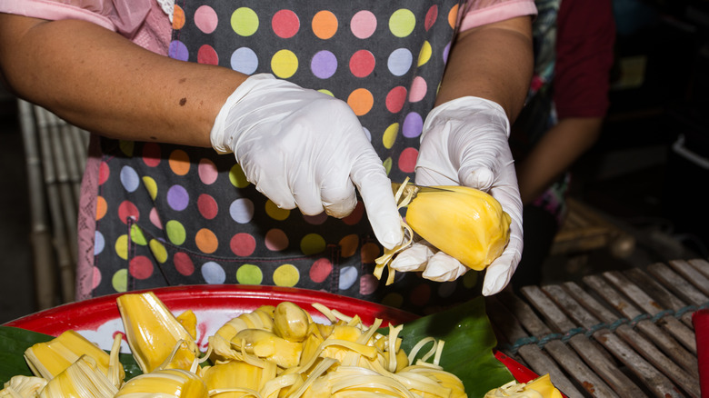 Gloved hands cutting jackfruit