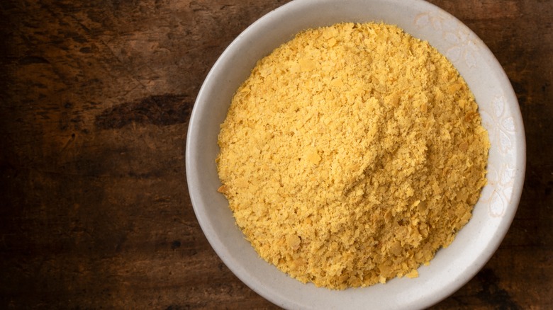 white bowl of nutritional yeast on wooden background