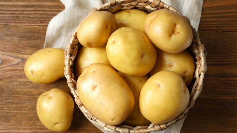 potatoes in basket on white sheet with wood background