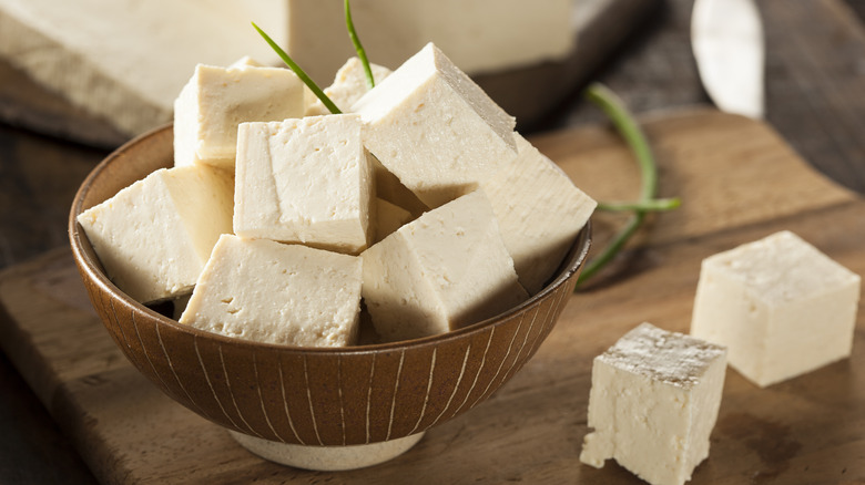 cubed tofu in brown bowl on wood cutting board