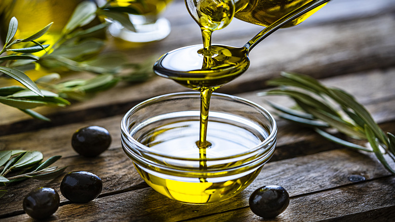 person pouring extra virgin olive oil onto spoon