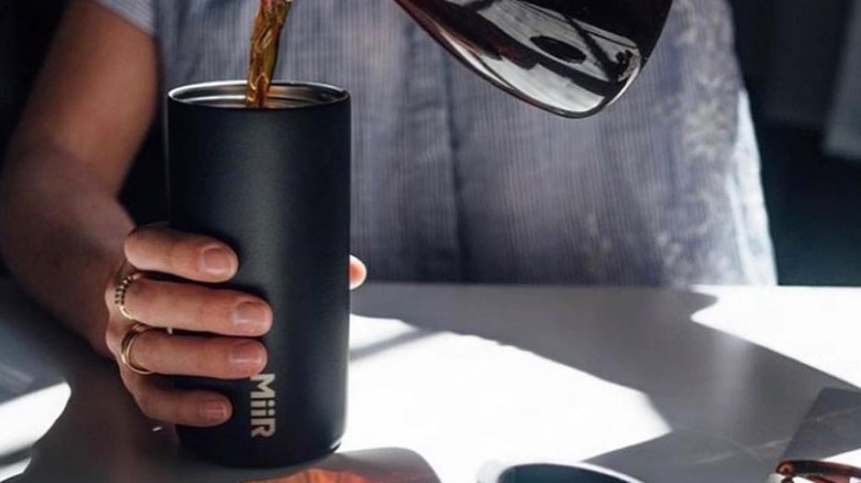 pouring coffee into black tumbler