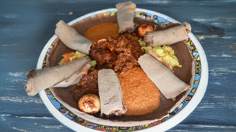 Plate of Ethiopian food and injera on wooden table