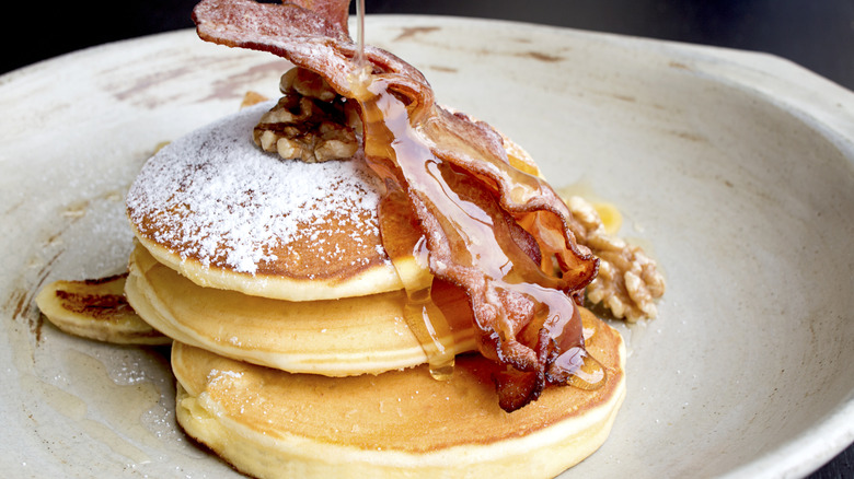 Stack of pancakes with bacon, nuts, and honey